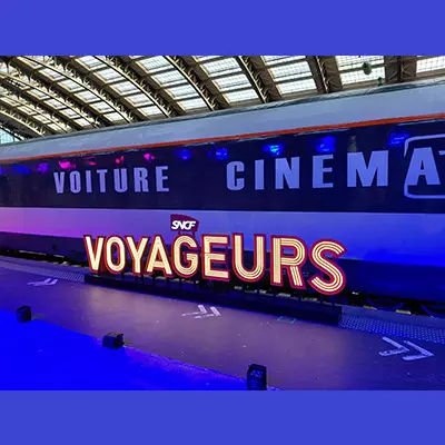 Vue latérale d’une voiture de train événementielle située à quai en Gare de Lille Flandres, à l’occasion du festival Séries Mania. La voiture est floquée “Voiture Cinéma”